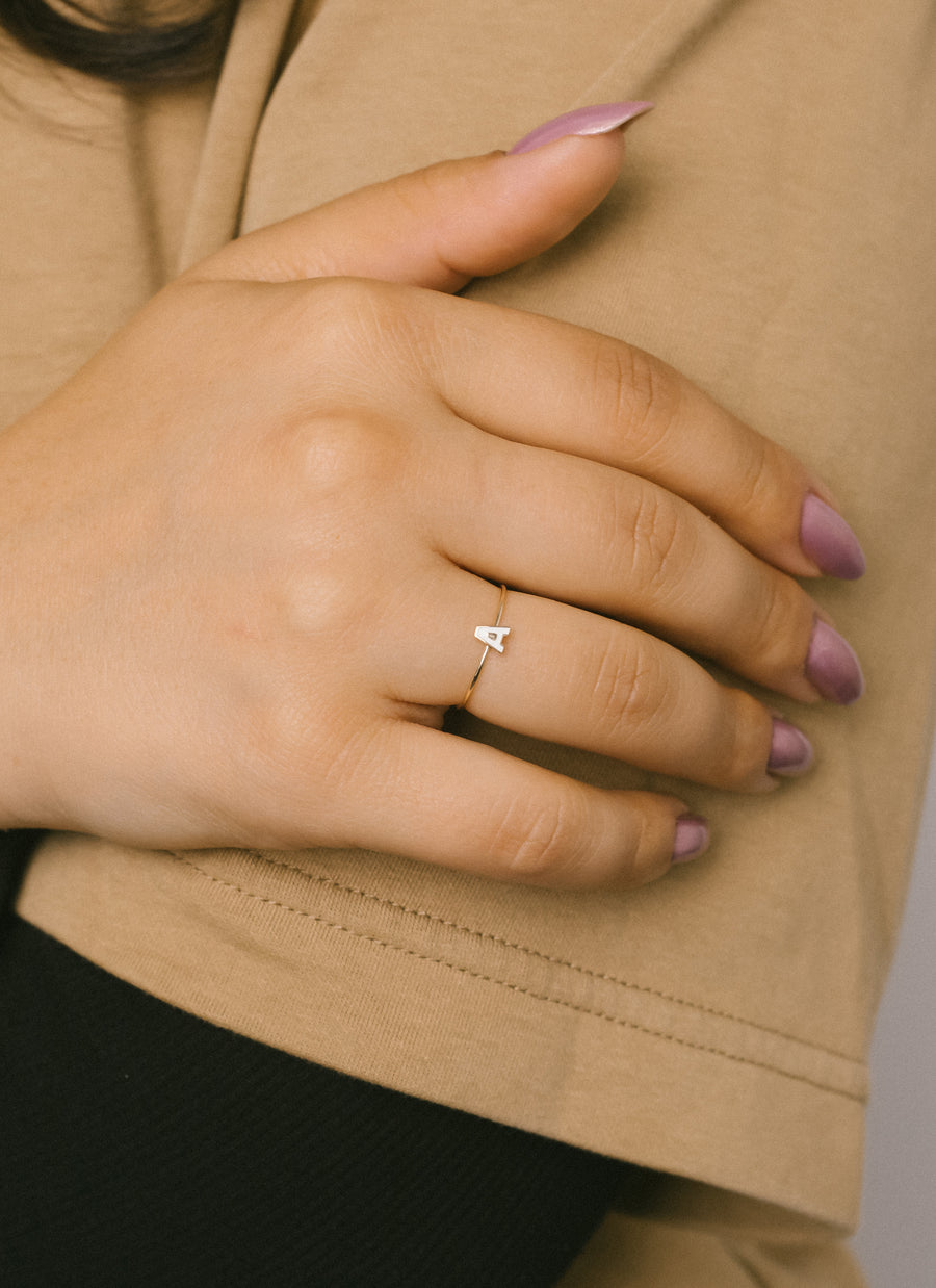 Model wears enamel letter A stacking ring from RIVA New York, in 14k yellow gold
