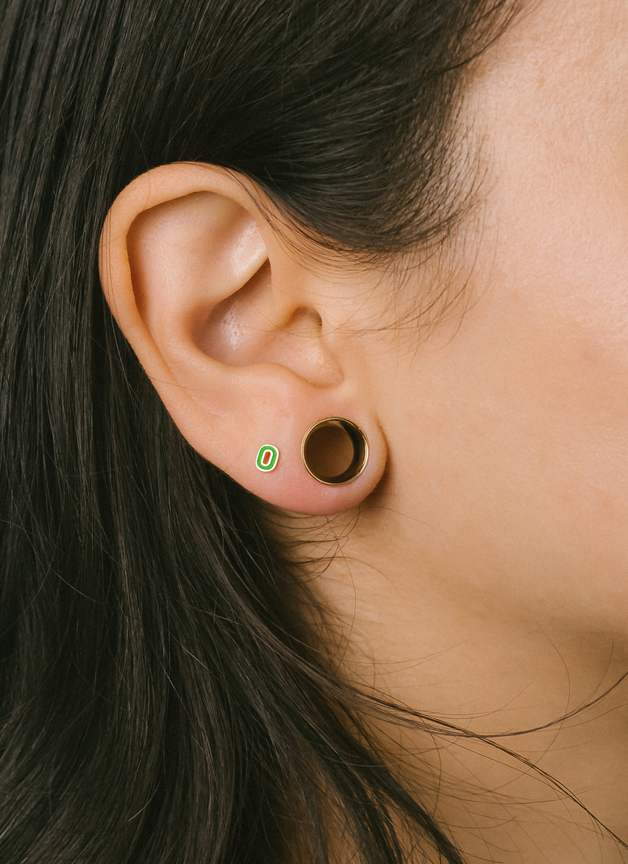 Piercing model wears mini enamel letter O stud earring in 14-karat yellow gold from RIVA New York jewelry