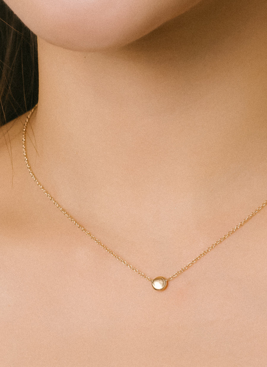 Closeup photo of model wearing RIVA New York's gold grain necklace in Fairmined Ecological gold