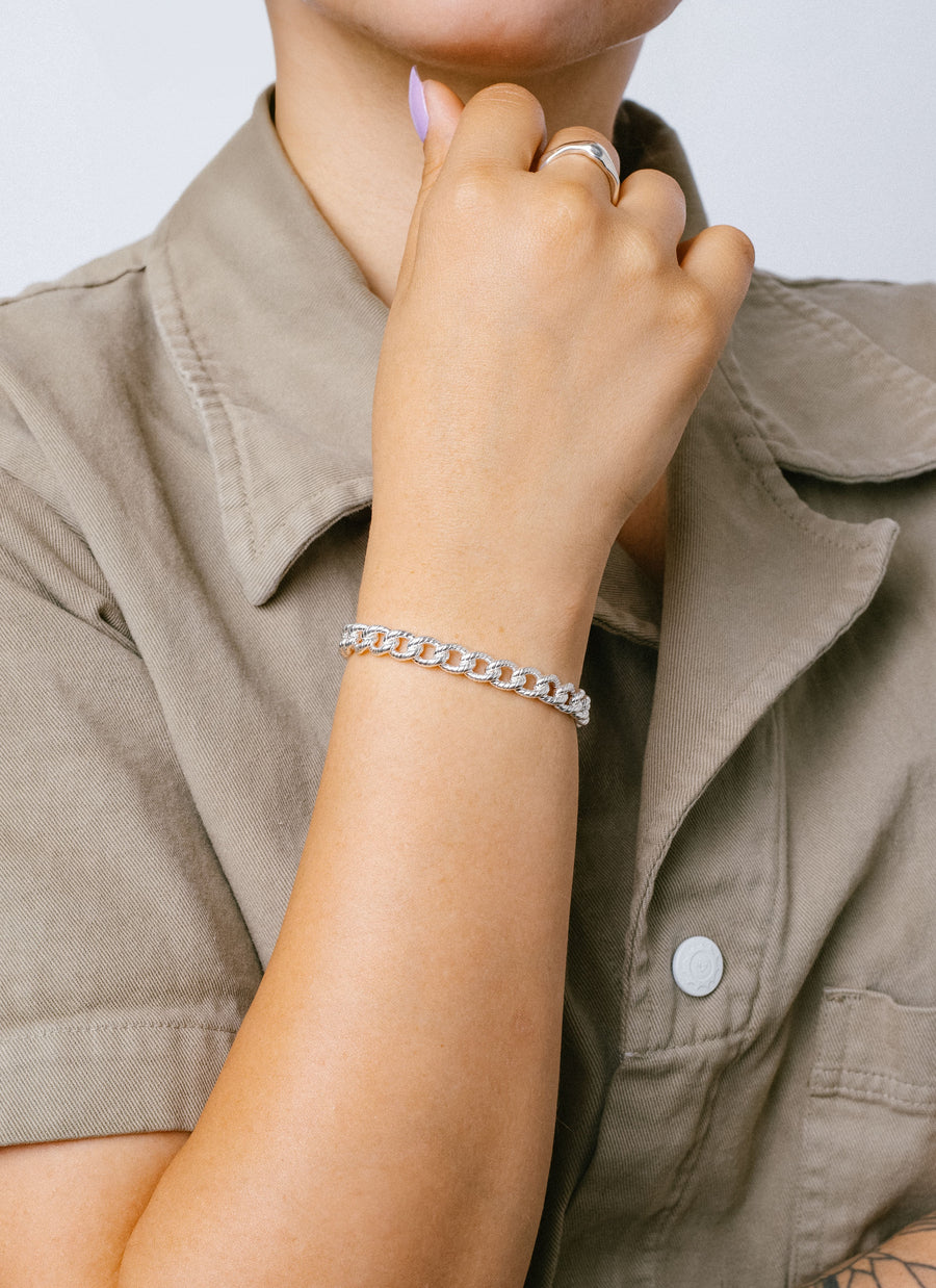 Female hand model wearing the Sterling Silver Textured curb chain bracelet from RIVA New York