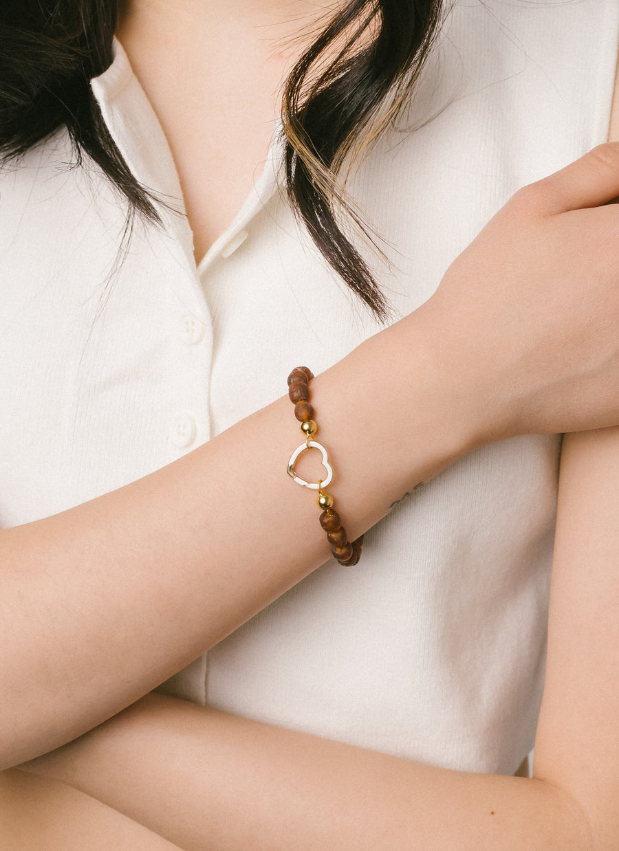 The RIVA New York Cobble specked brown recycled glass bead bracelet, worn with a heart-shaped Invisible Clasp