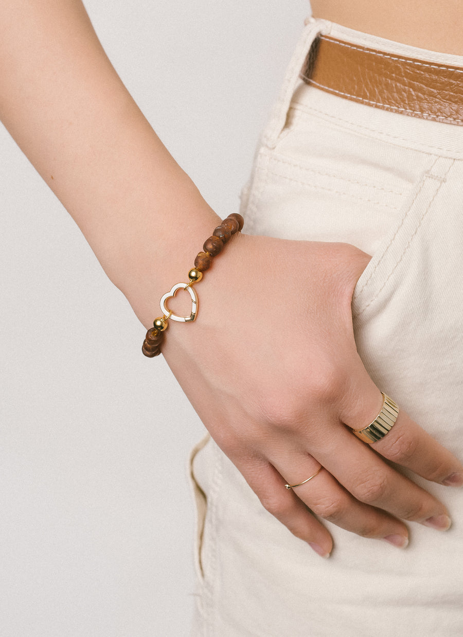 Model Hannah wears RIVA New York's Cobble specked brown recycled glass bead bracelet with a heart-shaped Invisible Clasp