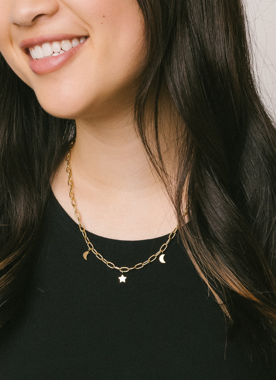 Charm necklace from RIVA New York featuring star and moon charms dangling from a rounded paper clip chain, seen here in gold vermeil