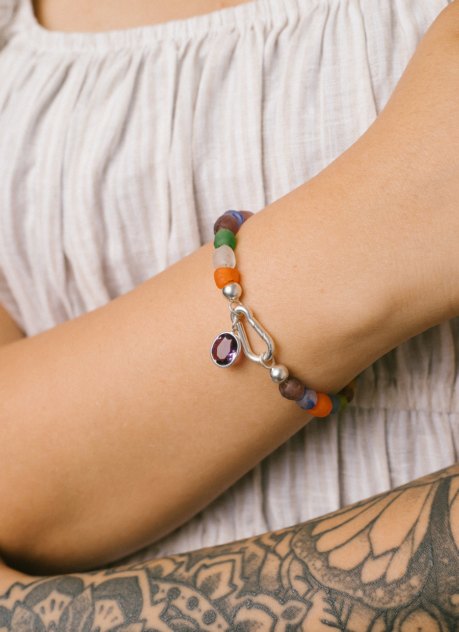 RIVA New York's Luna multicolor recycled glass bead bracelet with sterling silver accent; shown here with carabiner shaped clasp and oval amethyst charm