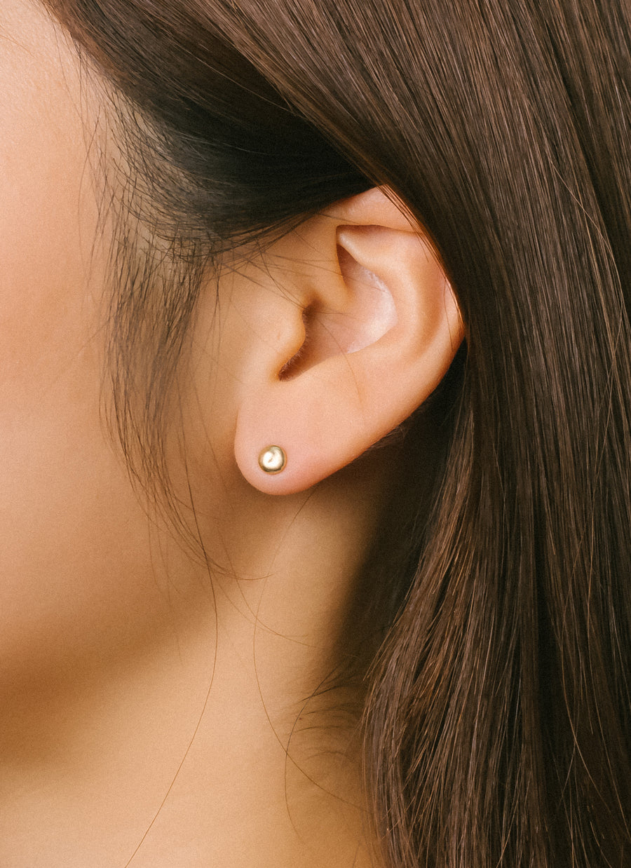 Model wears RIVA New York's gold grain stud earrings made of Fairmined Ecological gold