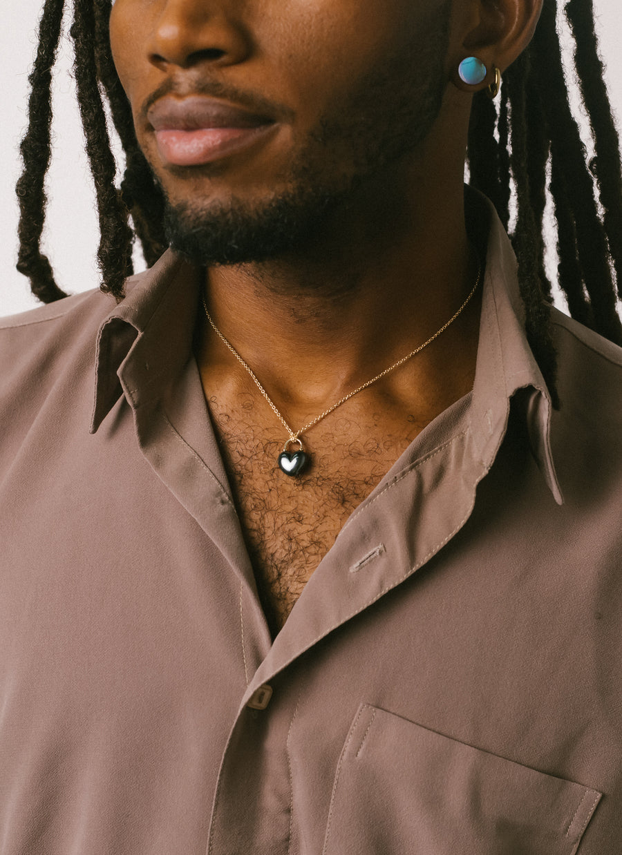 Male model wears RIVA Mew York's Hematite Heart Lock Pendant Necklace