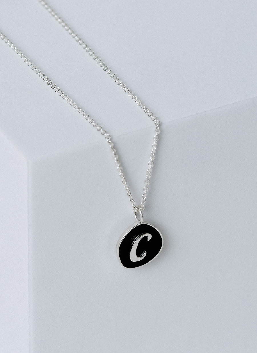 Script letter on black enamel pendant from RIVA New York, in recycled sterling silver; comes with 18" cable chain