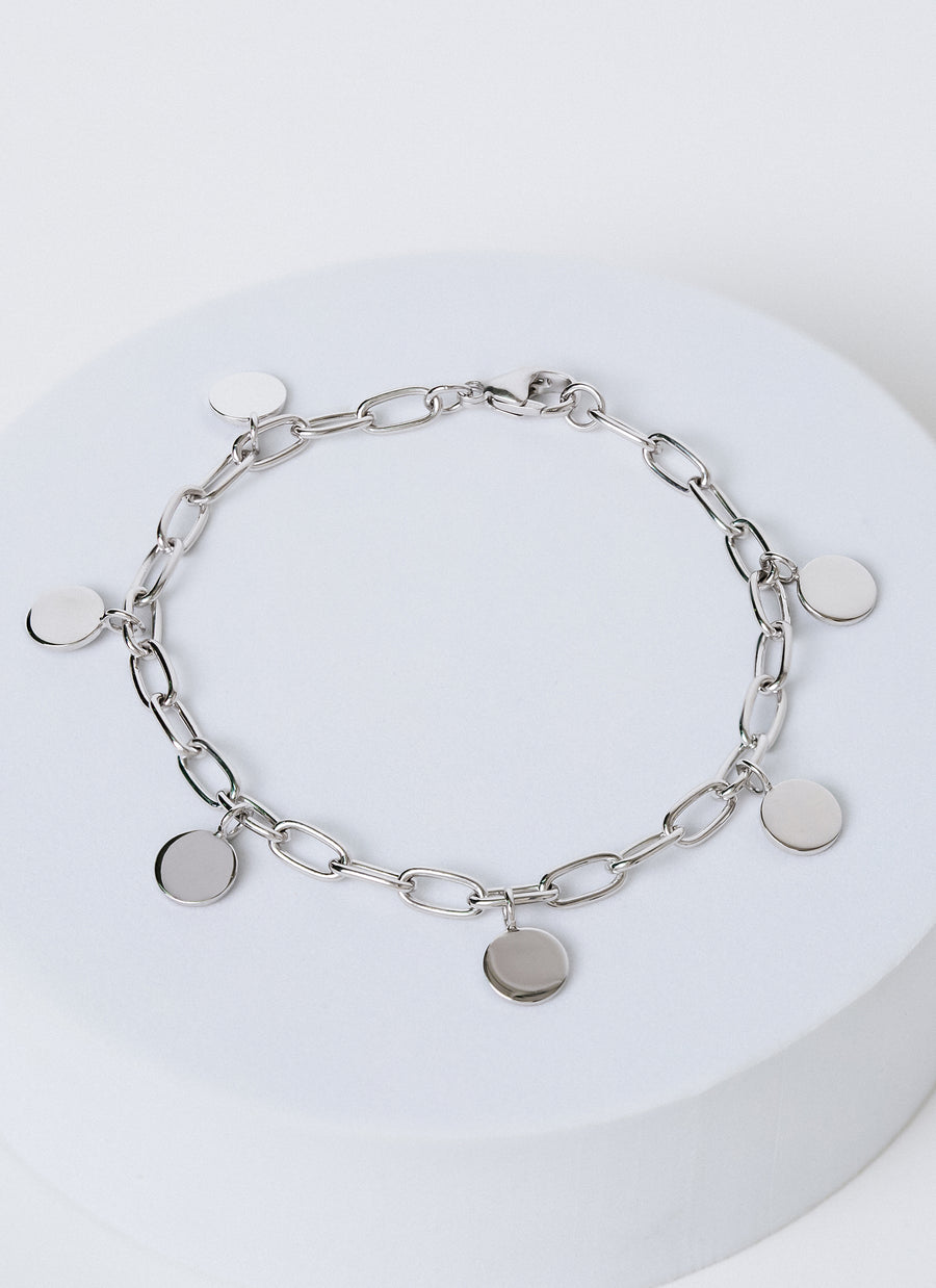 Silver charm bracelet from RIVA New York featuring circle or disc charms dangling from a paper clip chain