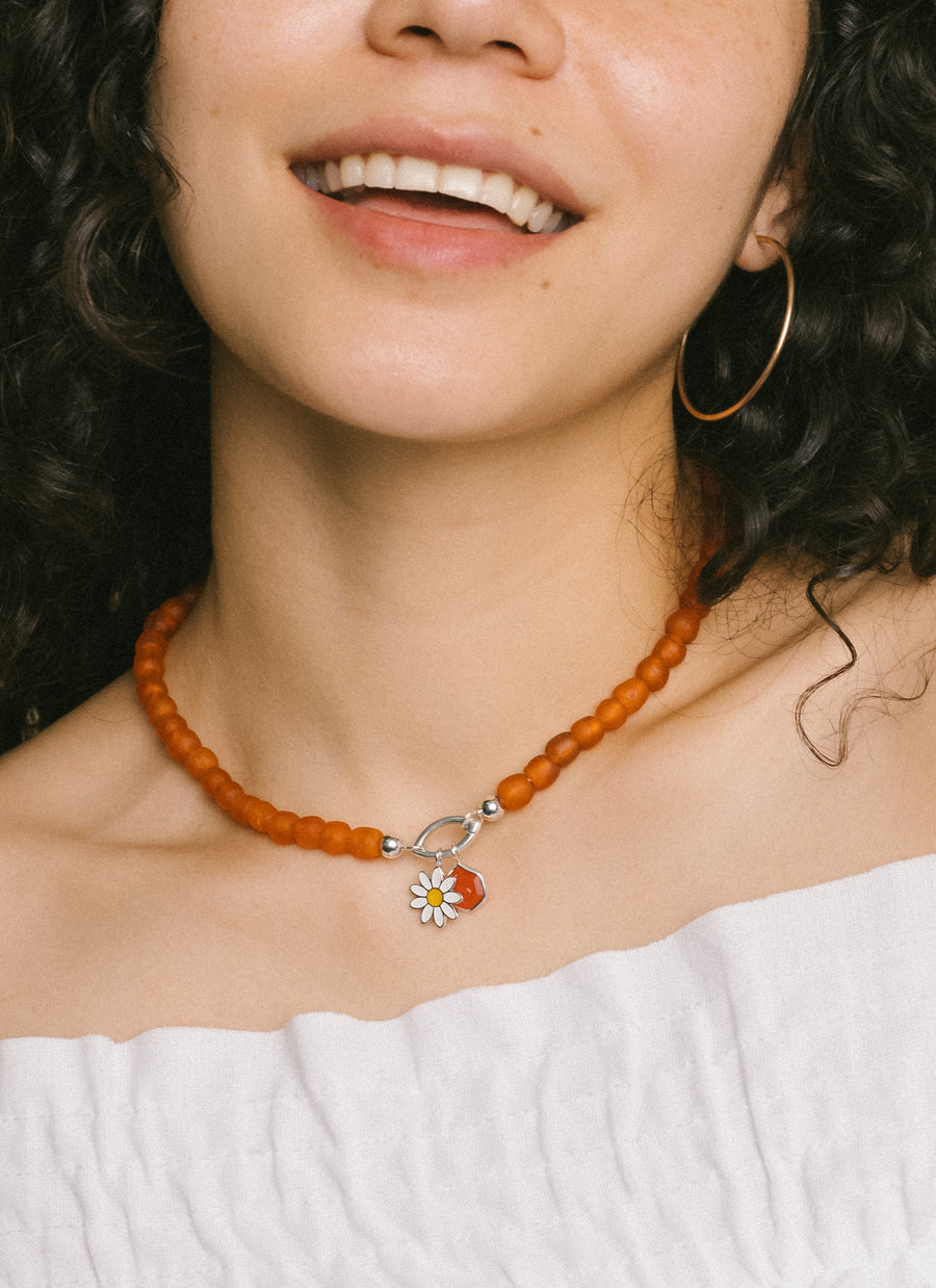 Celina Santana wears RIVA New York's Sunset orange recycled glass bead necklace with charms and marquise-shaped Invisible Clasp