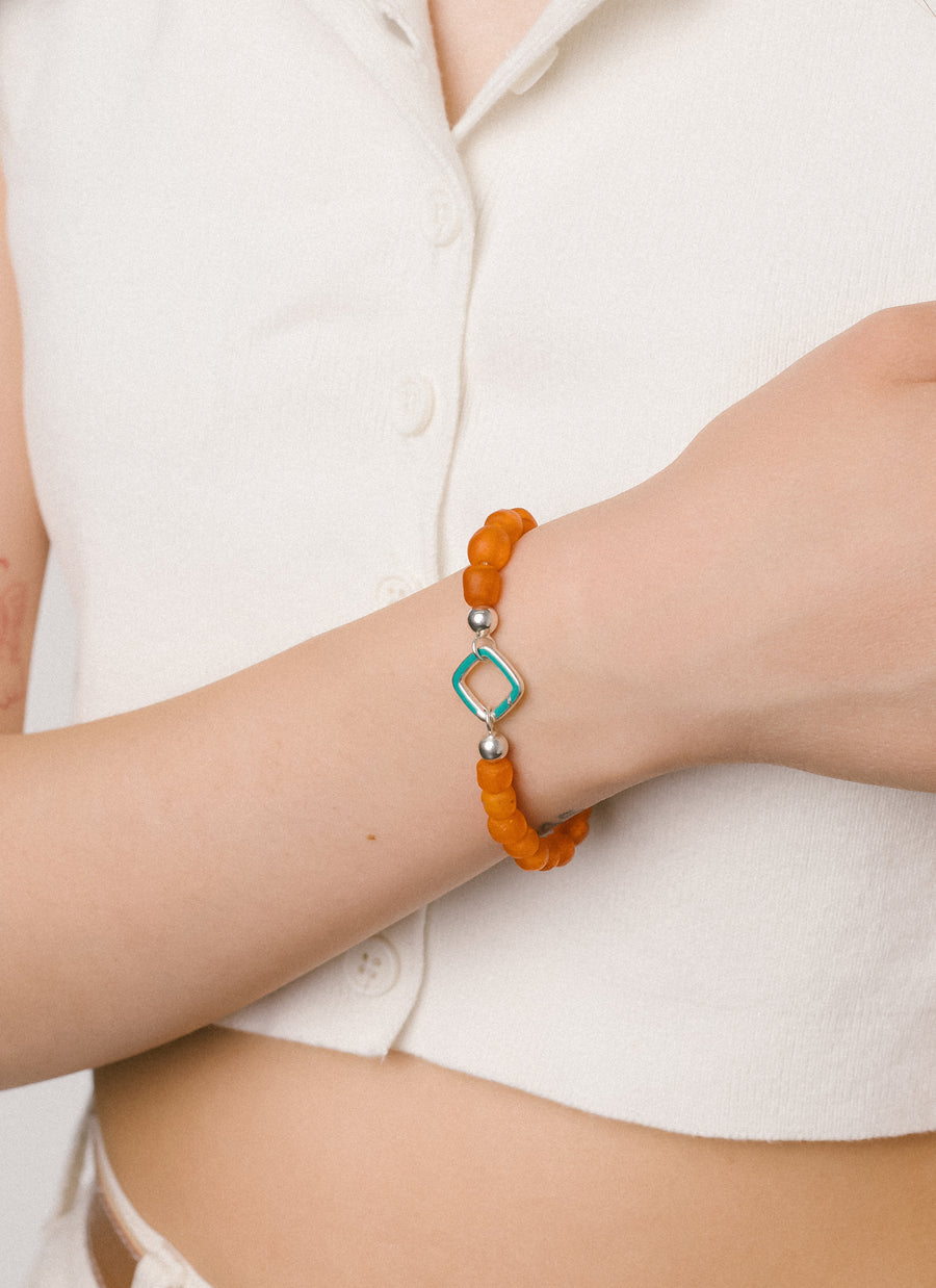The RIVA New York Sunset bead bracelet is made of orange colored recycled glass beads from the Krobo people of Ghana, shown here with cushion shaped Invisible Clasp